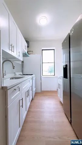 a kitchen with granite countertop a sink stove refrigerator and cabinets