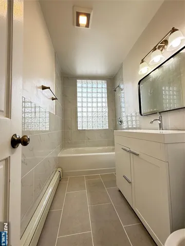 a bathroom with a tub sink and mirror