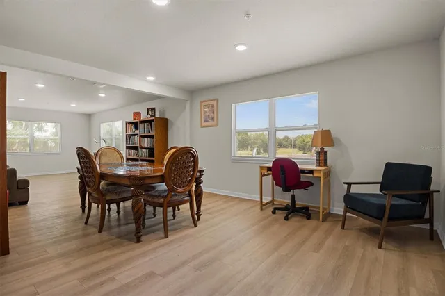 a living room with furniture and a dining table with bookshelf