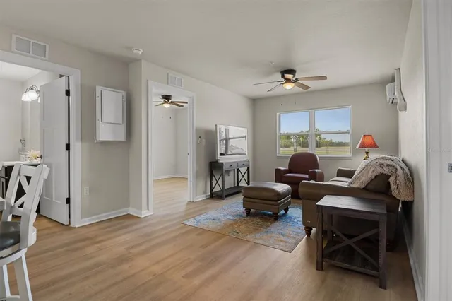 a living room with furniture a ceiling fan and a wooden floor