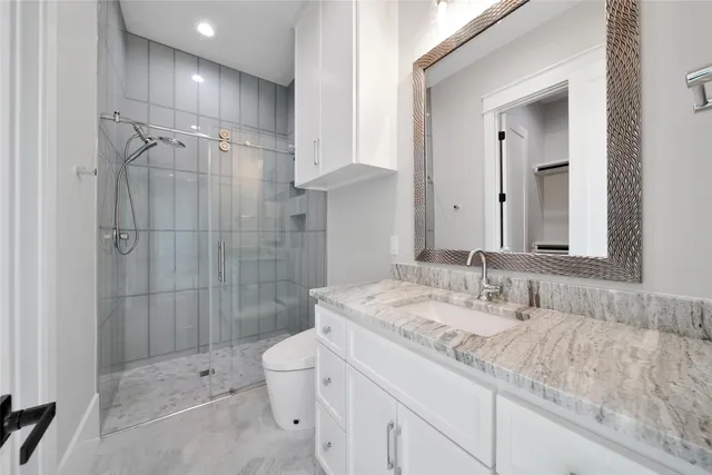 a bathroom with a granite countertop sink a toilet and shower