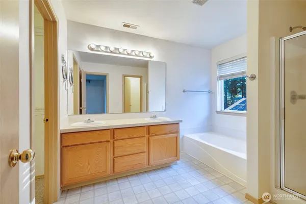 a spacious bathroom with a tub sink and mirror