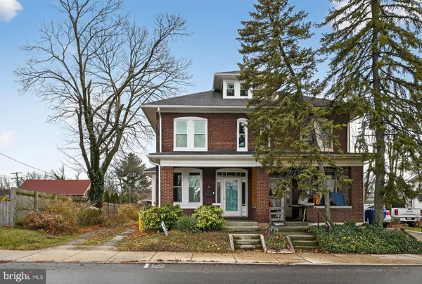 a front view of a house with garden and trees