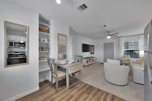 a living room with furniture a flat screen tv and kitchen view
