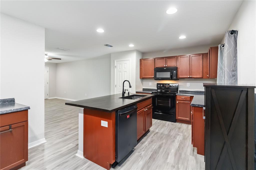 3723 Ricky Lane St. Cloud, FL 34772 - Photo 11 of 36 a kitchen with stainless steel appliances granite countertop a stove top oven a sink and dishwasher with wooden floor