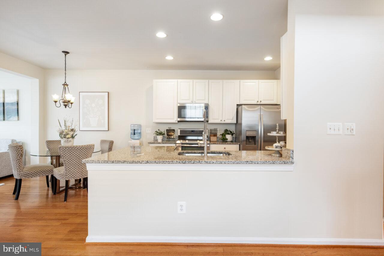 47799 Scotsborough Square Sterling, VA 20165 - Photo 11 of 53 a kitchen with stainless steel appliances granite countertop a sink a stove a dining table and chairs