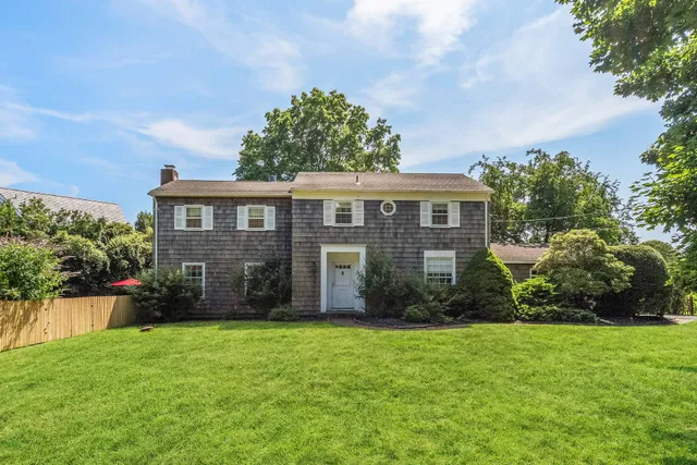 a view of a house next to a big yard and large trees
