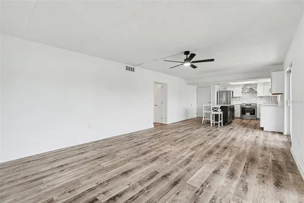a view of a livingroom with wooden floor and a ceiling fan