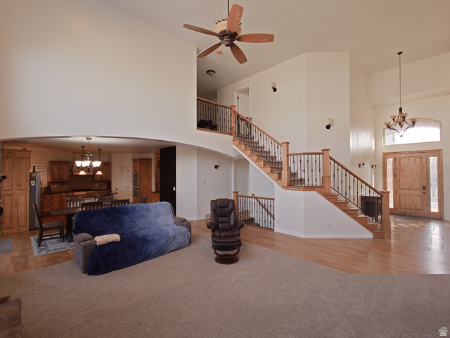 552 Sunset Crest Way Draper, UT 84020 - Photo 12 of 68 Living area with a chandelier, a towering ceiling, light wood-type flooring, stairway, and light colored carpet