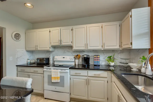 a kitchen with granite countertop white cabinets and white appliances