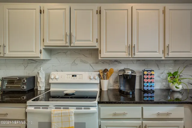 a kitchen with white cabinets and appliances