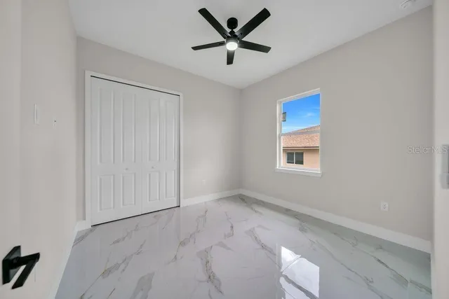 an empty room with ceiling fan and window