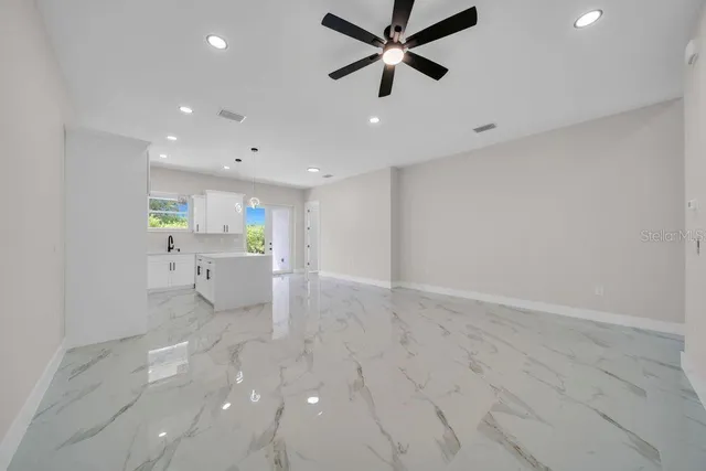 an empty room with ceiling fan and window