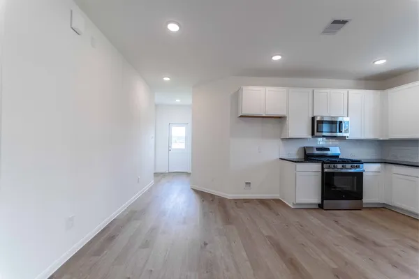 a kitchen with granite countertop a stove a sink and a refrigerator