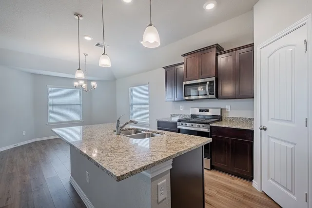 a kitchen with kitchen island granite countertop stainless steel appliances a sink stove and refrigerator