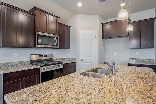 a kitchen with stainless steel appliances granite countertop a sink stove microwave and refrigerator