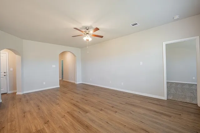 an empty room with wooden floor and fan