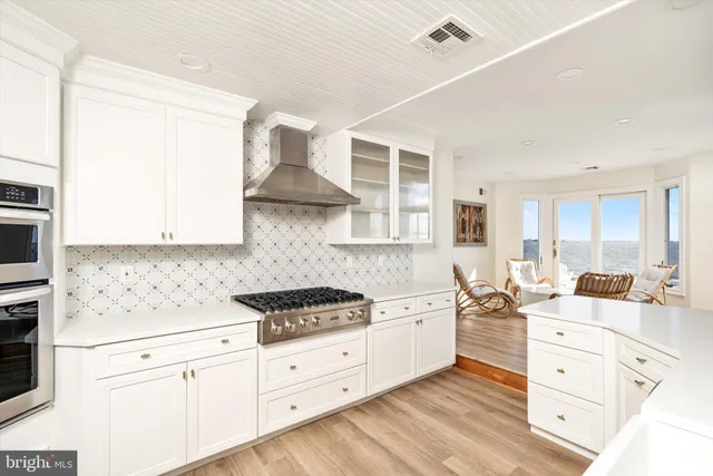 a kitchen with a sink a stove and white cabinets with wooden floor