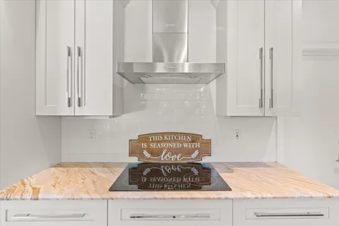 a kitchen with granite countertop white cabinets and a stove