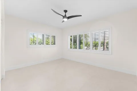 an empty room with windows and ceiling fan view