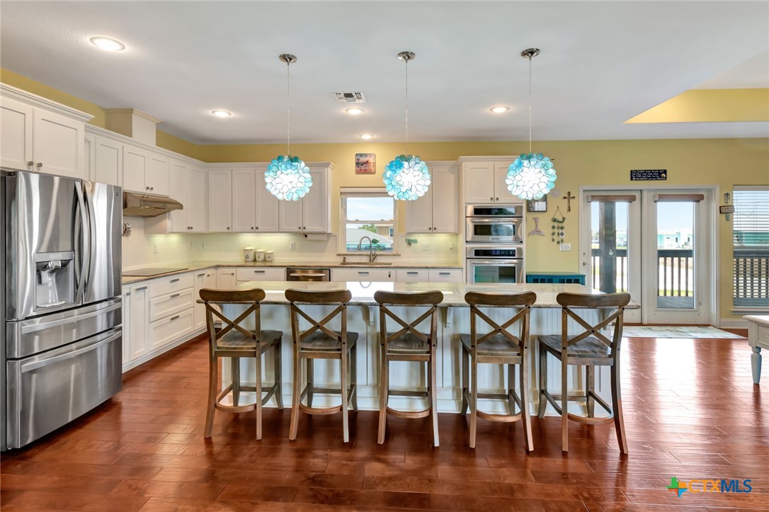 23 Macey Street Port O'Connor, TX 77982 - Photo 12 of 40 a kitchen with stainless steel appliances granite countertop a stove top oven a sink with island and chairs