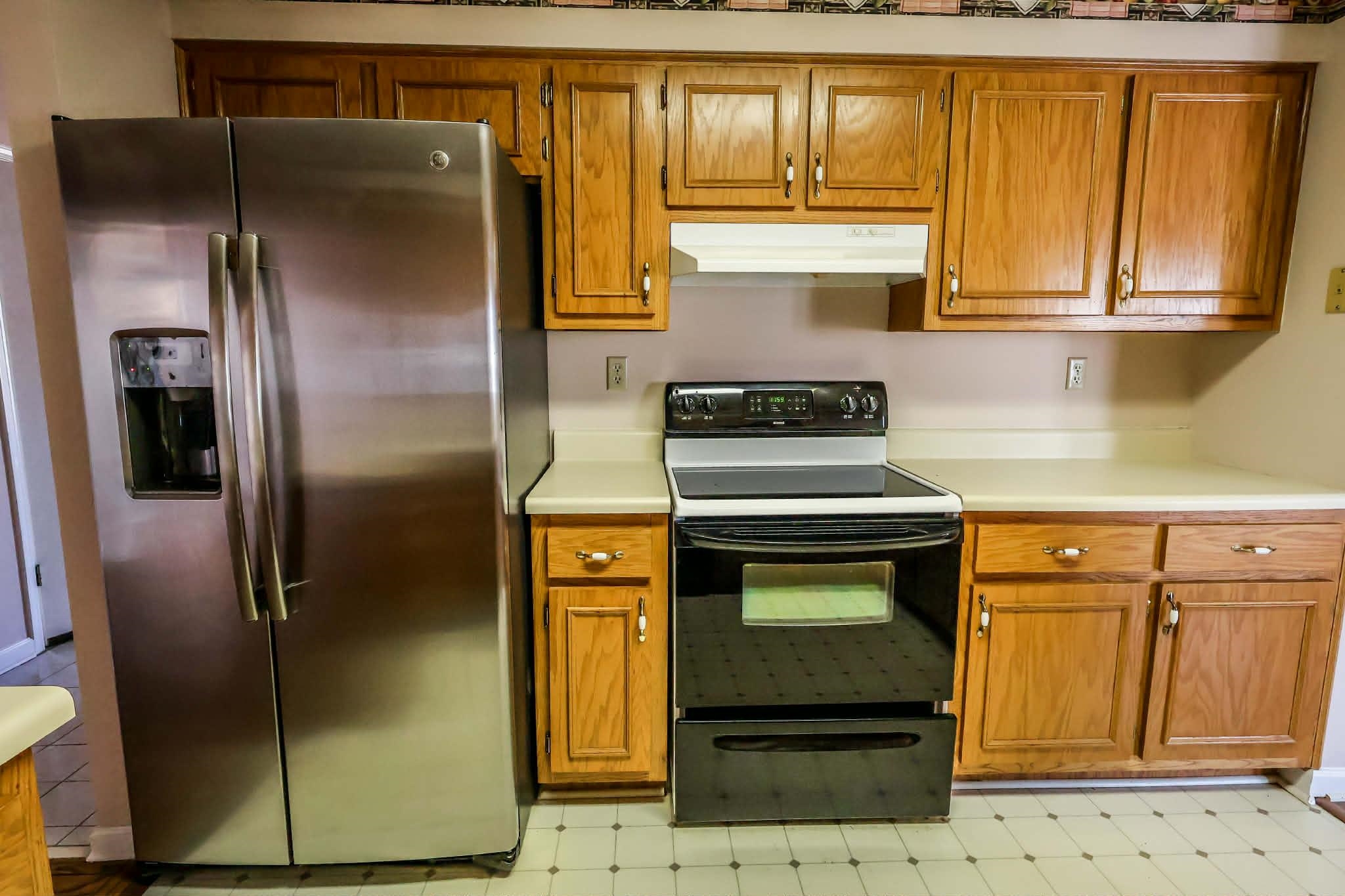 8712 Gragg Road Millington, TN 38053 - Photo 17 of 36 Kitchen with black / electric stove, stainless steel refrigerator with ice dispenser, light floors, light countertops, and wood finish cabinets