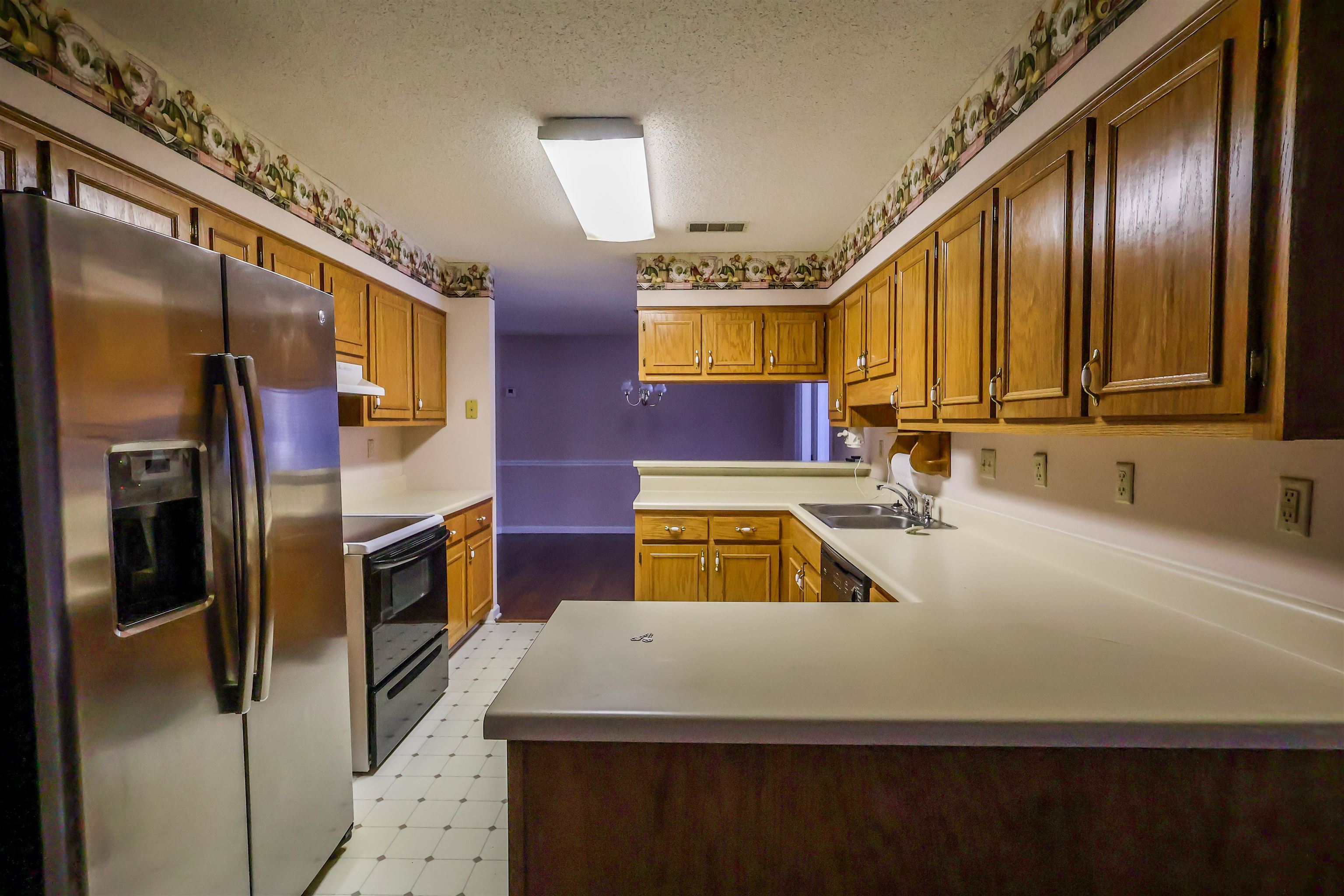 8712 Gragg Road Millington, TN 38053 - Photo 19 of 36 Kitchen with black appliances, light floors, wood finish cabinets, a peninsula, and a textured ceiling