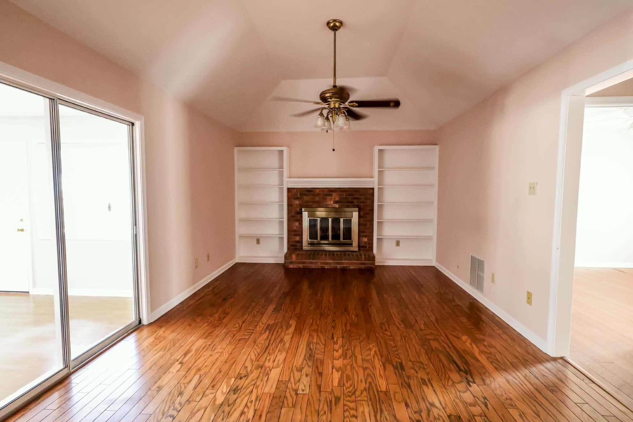 8712 Gragg Road Millington, TN 38053 - Photo 22 of 36 Unfurnished living room with dark wood-style flooring, a ceiling fan, a brick fireplace, and vaulted ceiling