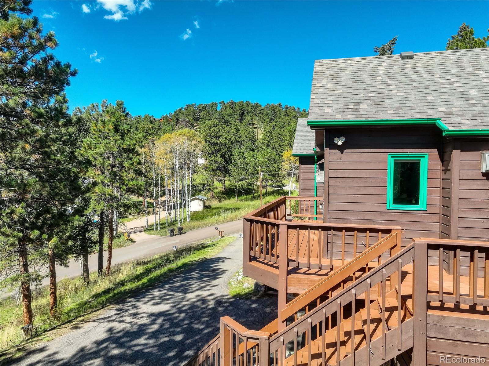 9758 Fallen Rock Road Conifer, CO 80433 - Photo 29 of 42 a view of a house with wooden stairs and fence