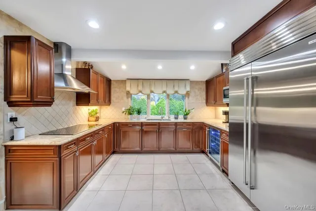 a large kitchen with stainless steel appliances granite countertop a refrigerator and a sink