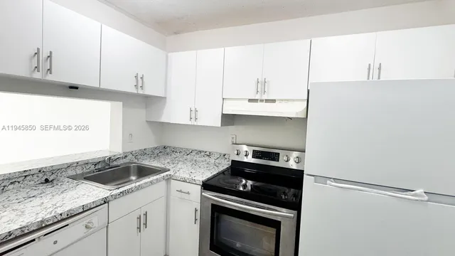 a kitchen with granite countertop white cabinets and white appliances