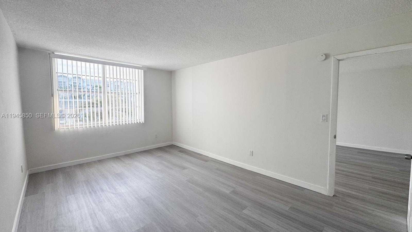 484 Northwest 165th St Road, Unit A314 Miami, FL 33169 - Photo 18 of 35 a view of an empty room with wooden floor and a window