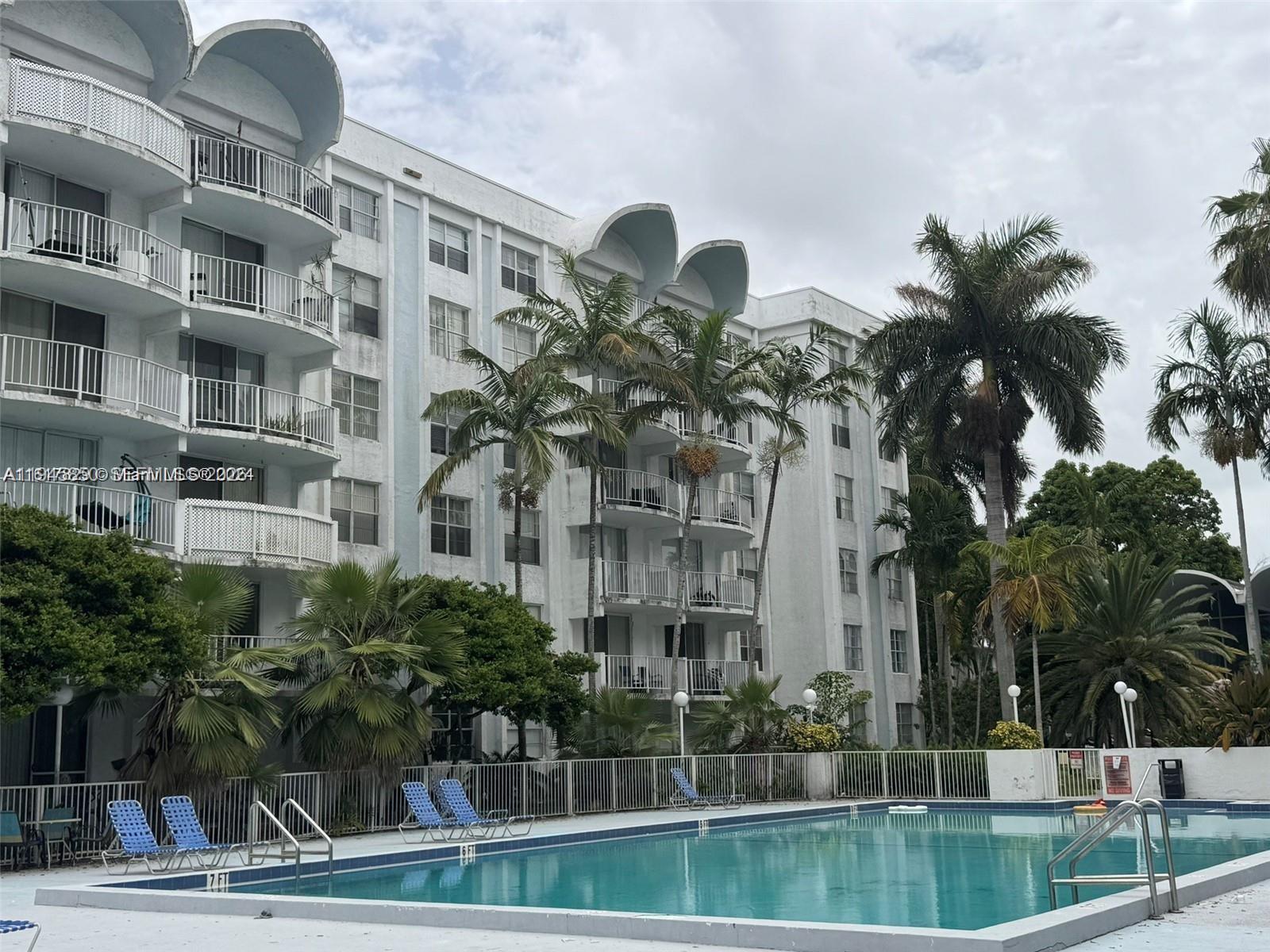 484 Northwest 165th St Road, Unit A314 Miami, FL 33169 - Photo 28 of 35 a front view of multi story residential apartment building with yard and sign board
