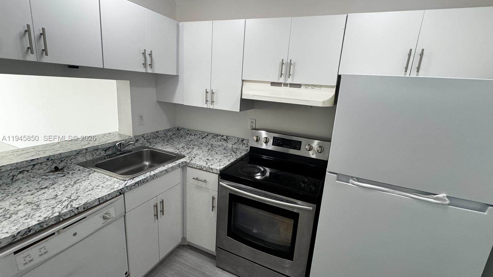 484 Northwest 165th St Road, Unit A314 Miami, FL 33169 - Photo 9 of 35 a kitchen with granite countertop white cabinets and black appliances