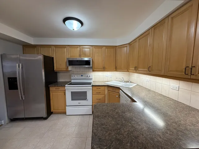 a kitchen with stainless steel appliances granite countertop a refrigerator a stove a sink and dishwasher