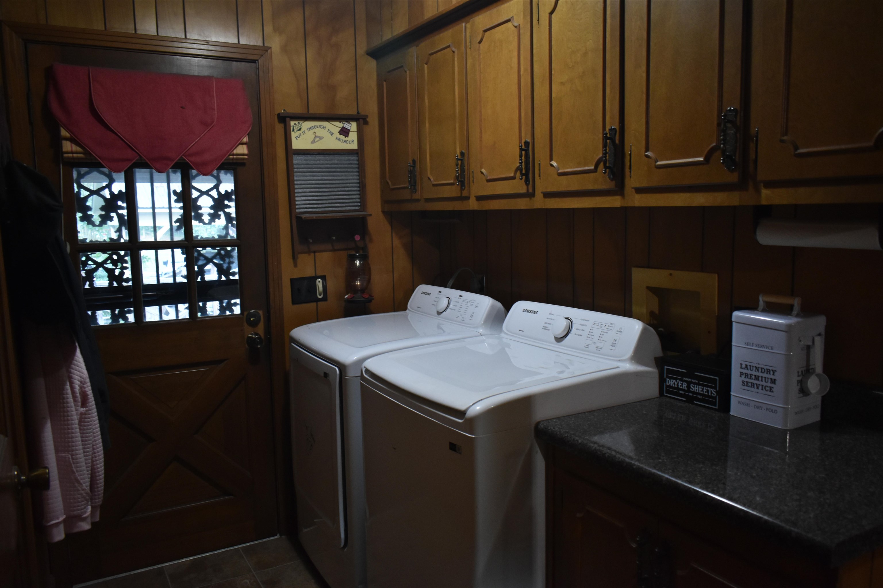 82 Ester Lane Ramer, TN 38367 - Photo 18 of 40 Laundry area featuring wood paneling, upper wood-finish cabinetry, and a dark stone-finish countertop