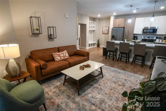 a living room with furniture a rug and kitchen view