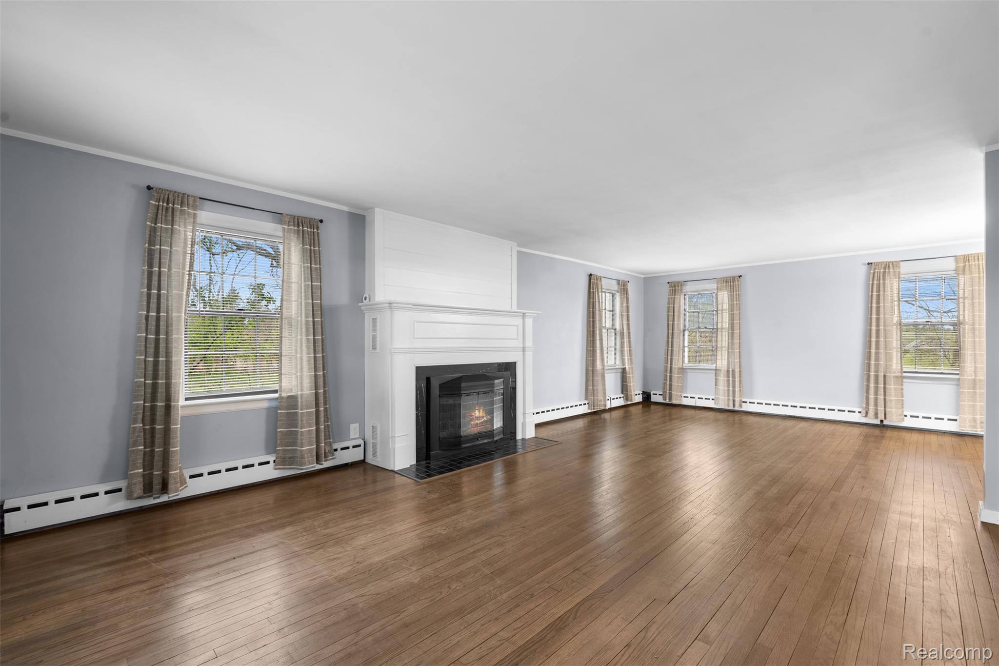 1775 Imlay City Road Lapeer, MI 48446 - Photo 8 of 60 Unfurnished living room with ornamental molding, dark wood finished floors, a baseboard radiator, and a fireplace with flush hearth
