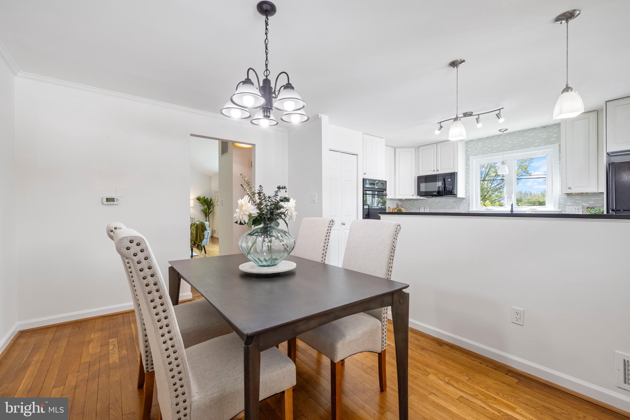 9821 Singleton Drive Bethesda, MD 20817 - Photo 7 of 45 a view of a dining room with furniture a chandelier and wooden floor
