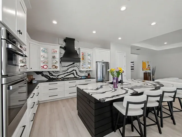 a kitchen with stainless steel appliances a stove a sink a refrigerator and white cabinets