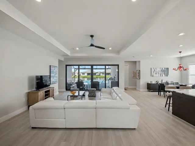 a living room with furniture kitchen area and a large window