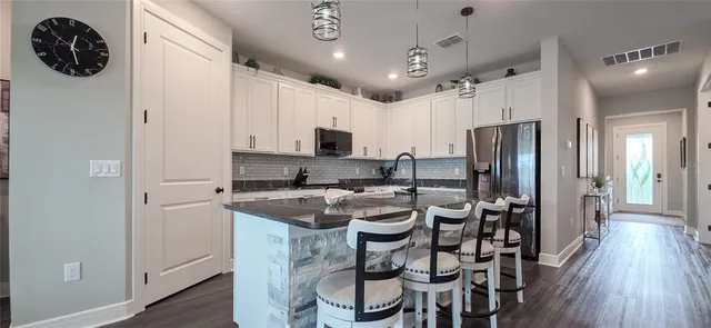 a kitchen with stainless steel appliances granite countertop a stove a sink and white cabinets