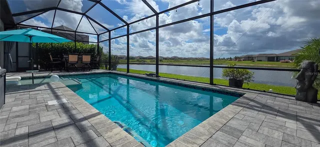 a view of swimming pool with a table and chairs under an umbrella