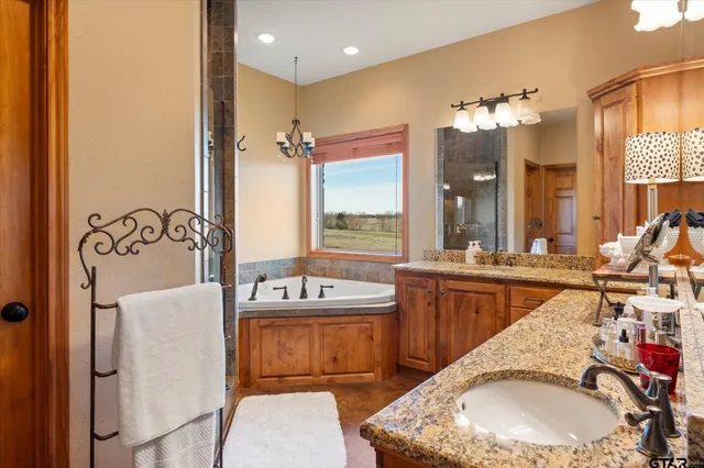 a en suite bathroom with a granite countertop double vanity sink mirror and bathtub