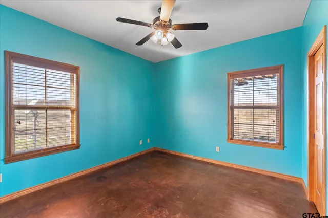 an empty room with windows and fan