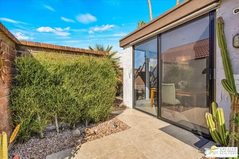 a view of a patio with table and chairs potted plants and floor to ceiling window