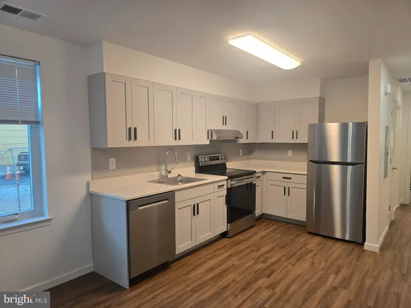 a kitchen with a refrigerator stove and wooden floor