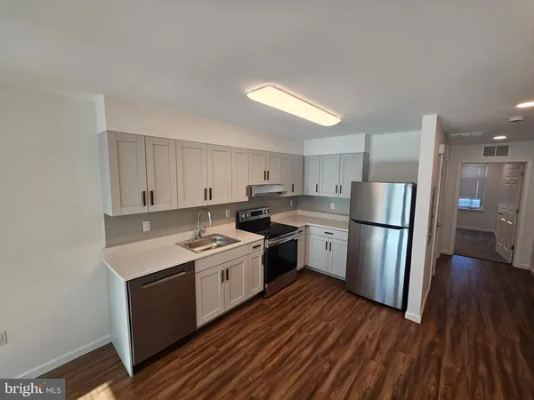 a kitchen with a sink a refrigerator a stove and wooden floor