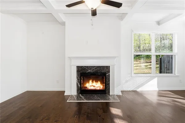 a view of an empty room with wooden floor fireplace and a window