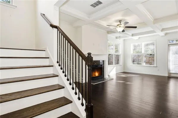 a view of an empty room with wooden floor fireplace and a window